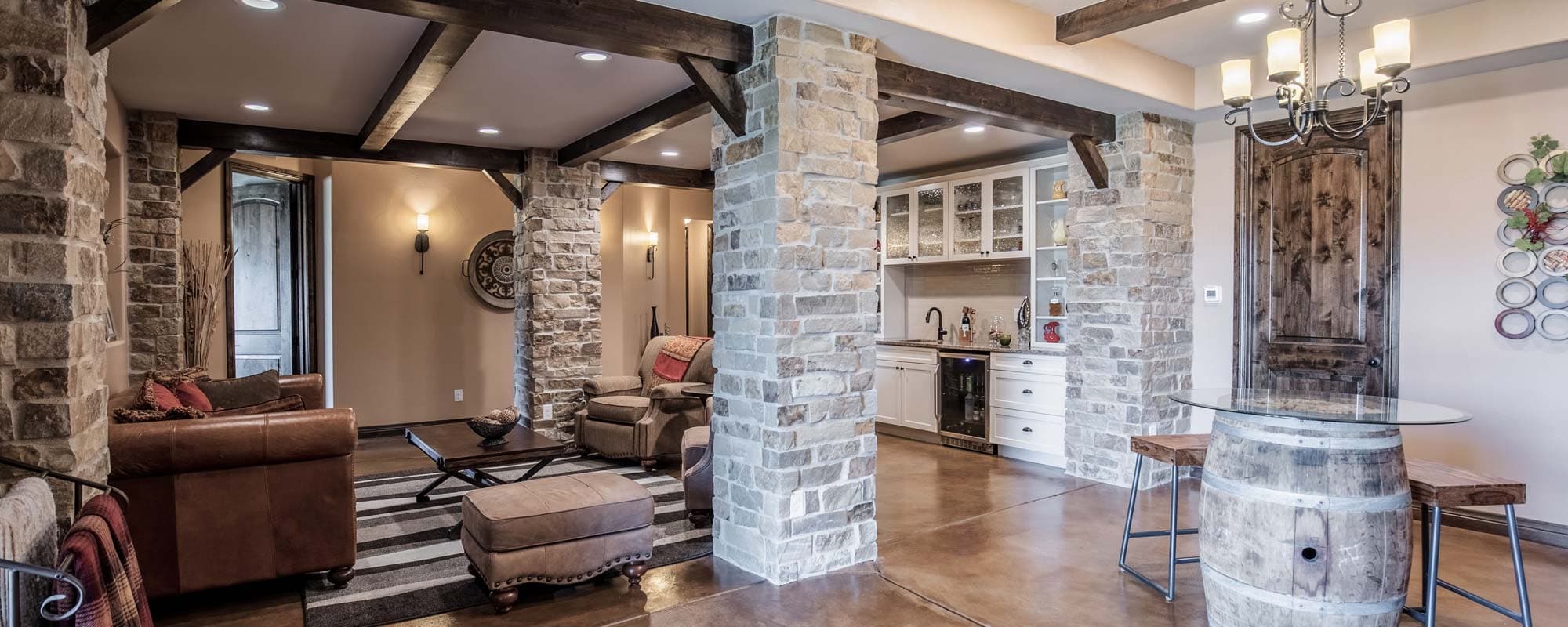 Finished basement lounge with stone columns and a bar